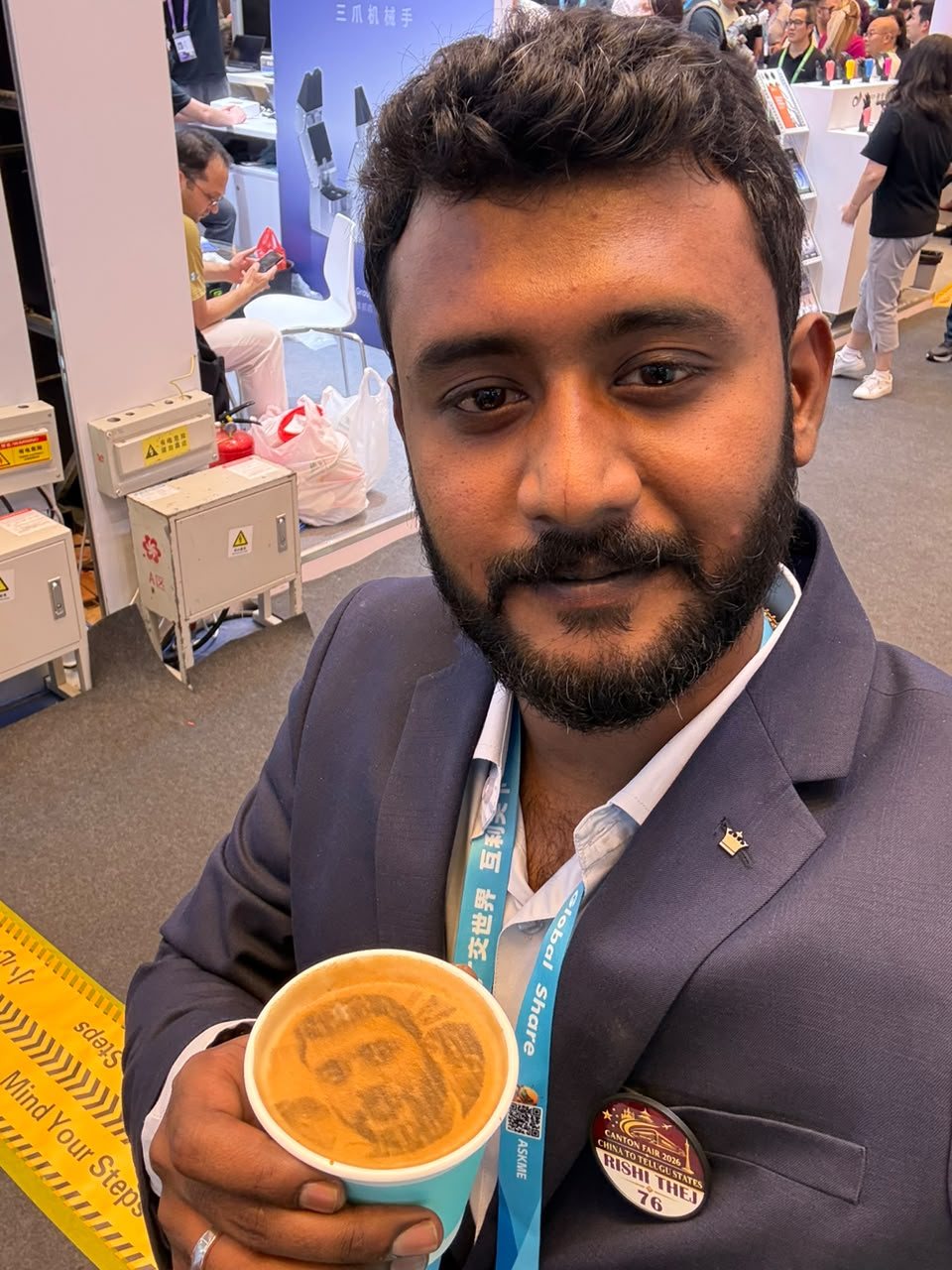 Bollam Rishithej holding a latte with his own face printed in the foam at the Canton Fair
