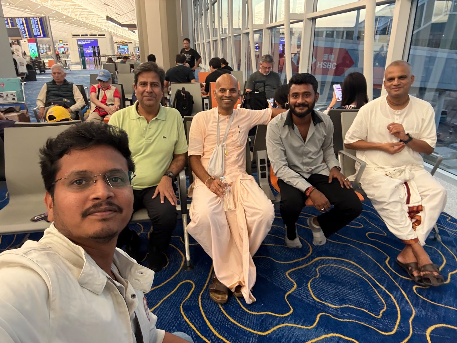 Bollam Rishithej with Mukesh Tiwari, Sai Kishor, Yagneshwara Dasa and Bharatarshabha Dasa at a departure gate in Hong Kong